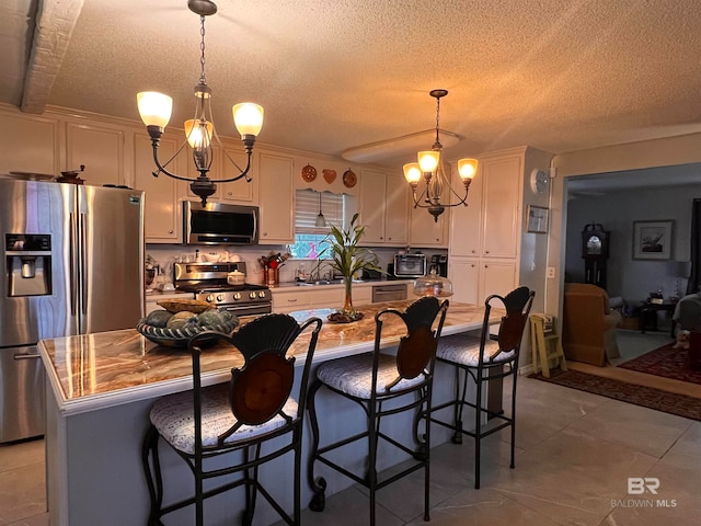 kitchen with a breakfast bar, stainless steel appliances, decorative light fixtures, an inviting chandelier, and a center island