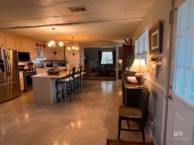 kitchen with stainless steel appliances, a healthy amount of sunlight, a kitchen island, hanging light fixtures, and a breakfast bar area