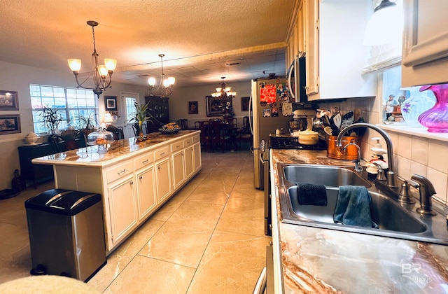 kitchen featuring sink, decorative light fixtures, a textured ceiling, appliances with stainless steel finishes, and a notable chandelier