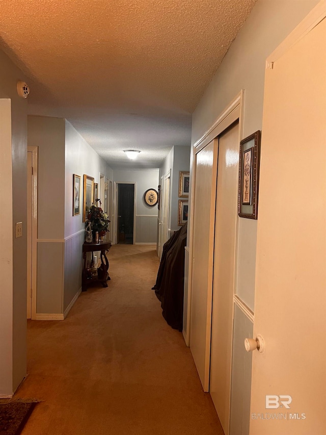 corridor featuring light colored carpet and a textured ceiling