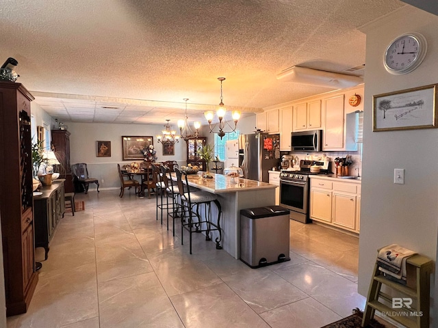 kitchen with a kitchen breakfast bar, stainless steel appliances, pendant lighting, a chandelier, and a kitchen island