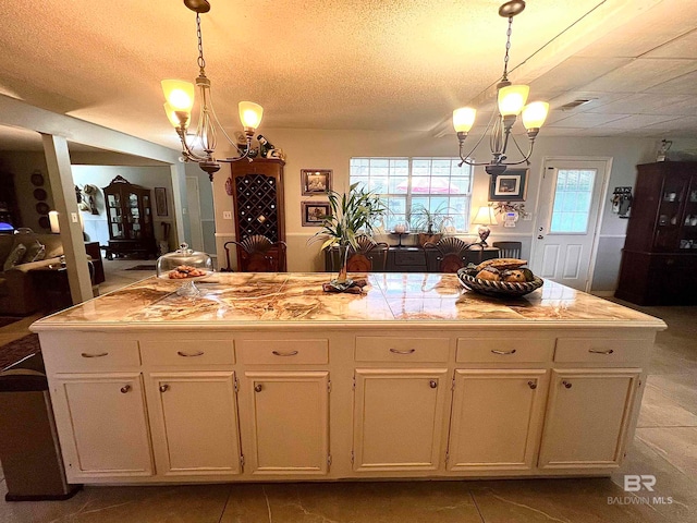 kitchen with white cabinets, a chandelier, decorative light fixtures, and a kitchen island