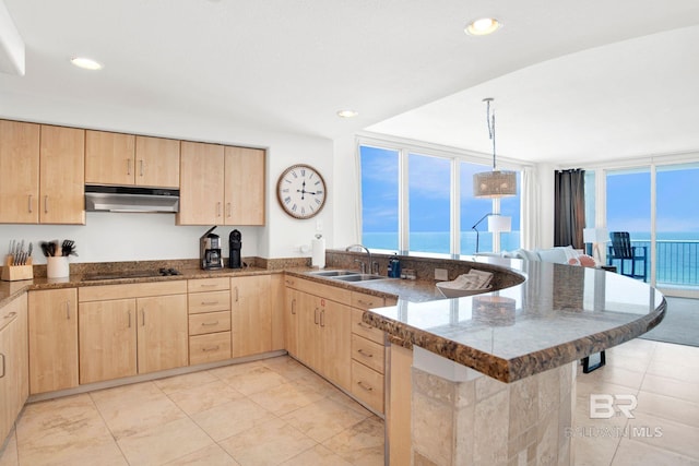 kitchen featuring light brown cabinetry, a sink, under cabinet range hood, and recessed lighting