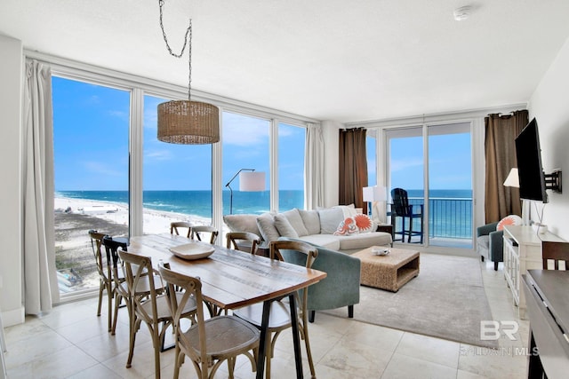 dining room featuring a wall of windows, light tile patterned flooring, and view of water and beach