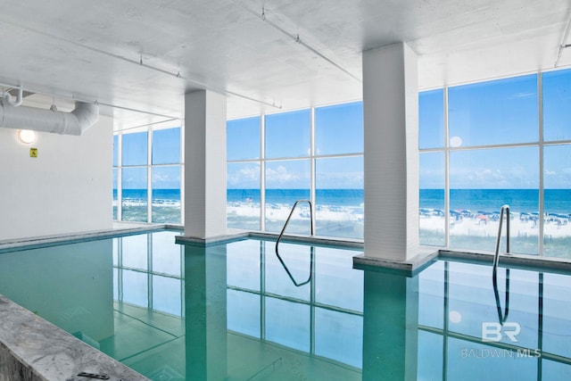 indoor community pool featuring view of water and beach