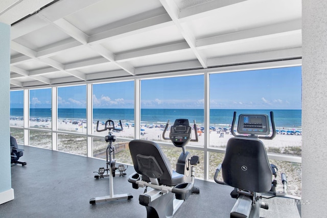 gym with floor to ceiling windows, beam ceiling, view of water and beach, and coffered ceiling