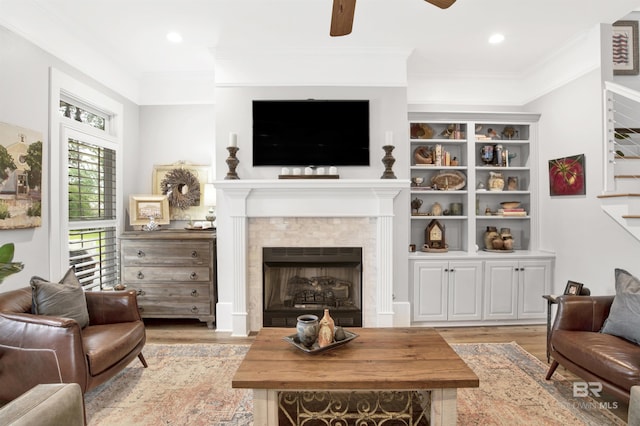 living room with crown molding, light hardwood / wood-style flooring, and ceiling fan