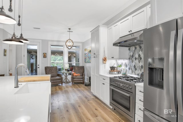 kitchen with stainless steel appliances, light hardwood / wood-style floors, decorative backsplash, white cabinets, and decorative light fixtures