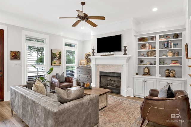 living room featuring ornamental molding, light hardwood / wood-style floors, and ceiling fan