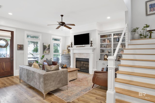 living room featuring crown molding, light hardwood / wood-style flooring, and ceiling fan