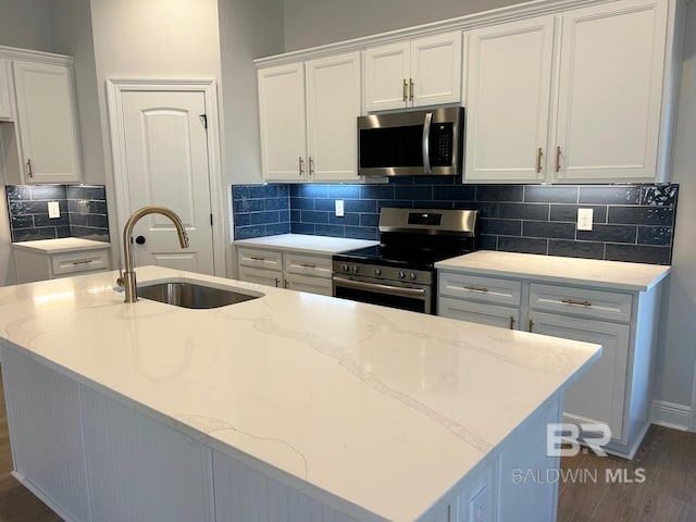 kitchen featuring appliances with stainless steel finishes, sink, dark hardwood / wood-style flooring, white cabinetry, and decorative backsplash