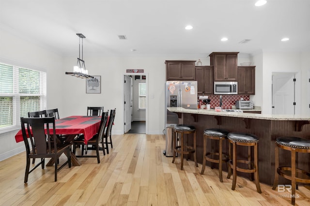 1246 Pembroke Way, Foley, AL 36535 - kitchen with appliances with stainless steel finishes, dark brown cabinets, plenty of natural light, a breakfast bar area, and recessed lighting