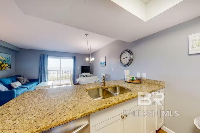 kitchen with white cabinets, light stone countertops, decorative light fixtures, sink, and a notable chandelier