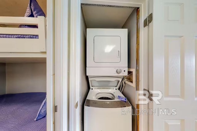 washroom featuring stacked washer / drying machine and carpet floors