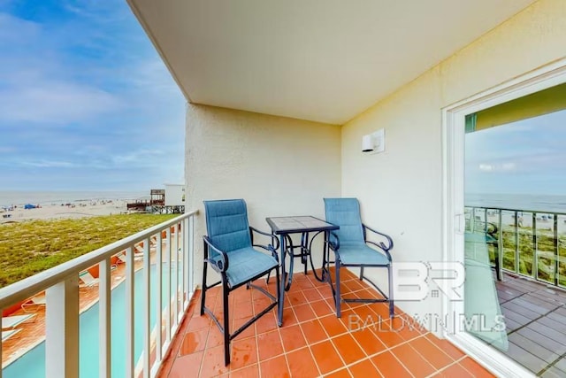 balcony with a water view and a view of the beach