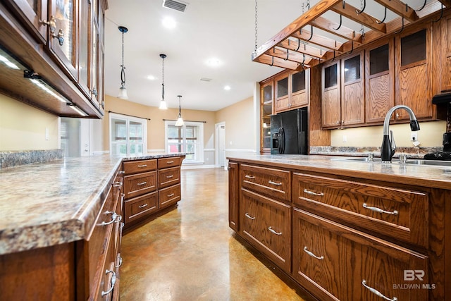 kitchen featuring black refrigerator with ice dispenser, sink, and decorative light fixtures