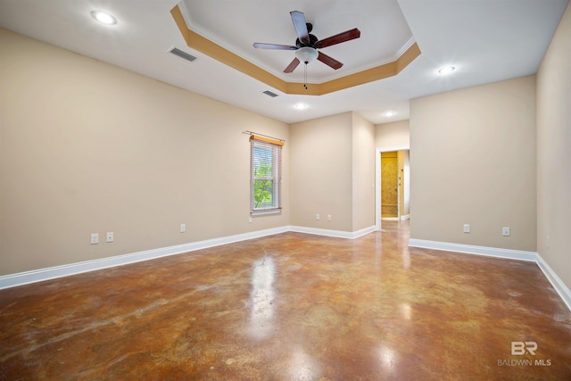 spare room featuring concrete flooring, ceiling fan, a raised ceiling, and ornamental molding