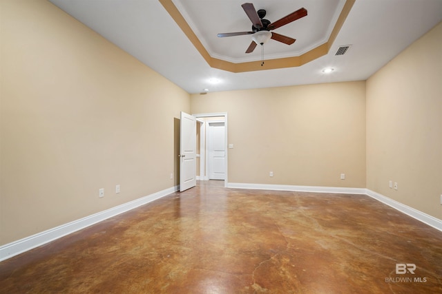 unfurnished room featuring ceiling fan, concrete floors, a raised ceiling, and crown molding