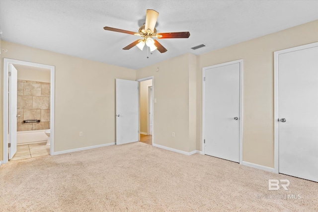 unfurnished bedroom with visible vents, light carpet, baseboards, and two closets