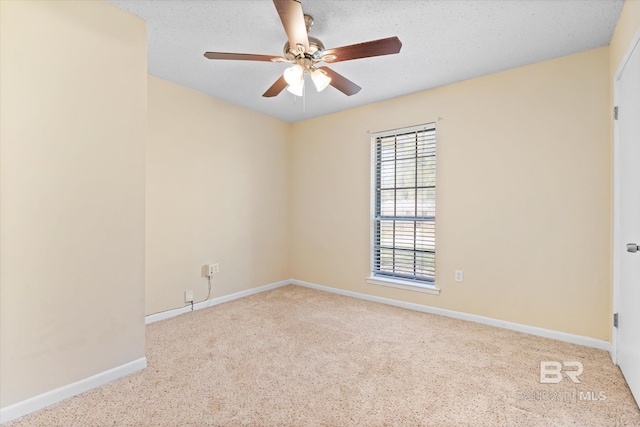 spare room with a textured ceiling, light carpet, a ceiling fan, and baseboards