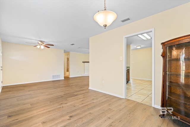 spare room with baseboards, visible vents, ceiling fan, and light wood finished floors