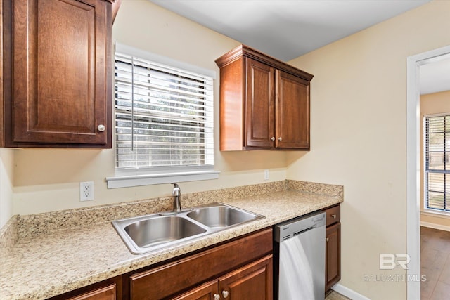 kitchen with baseboards, light countertops, dishwasher, and a sink