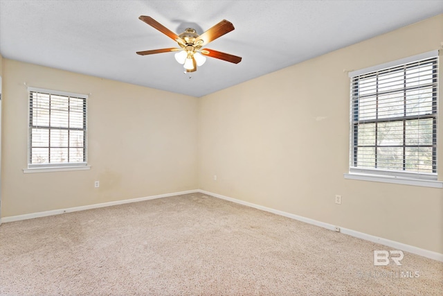 carpeted spare room with a ceiling fan and baseboards