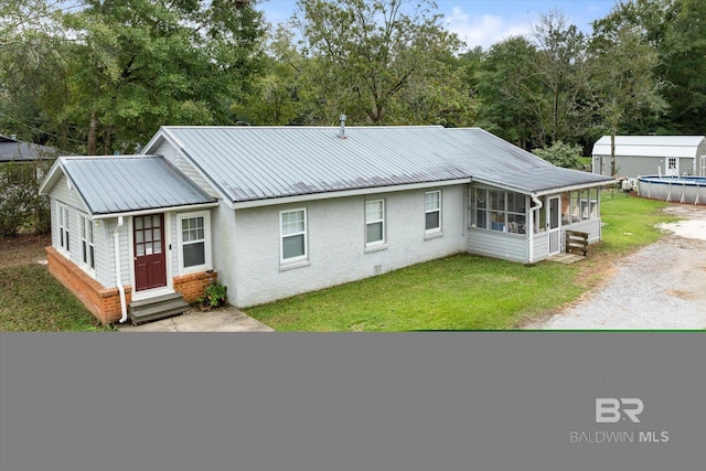 back of property with a lawn and a sunroom