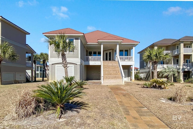 3214 Dolphin Dr, Gulf Shores, AL 36542 - view of front facade featuring a tiled roof, a porch, and stairs