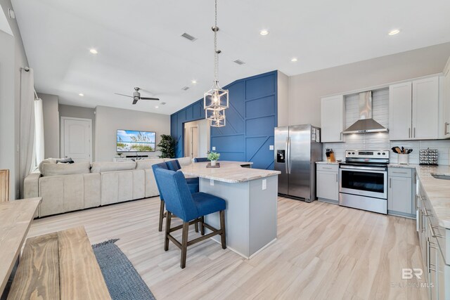 3214 Dolphin Dr, Gulf Shores, AL 36542 - kitchen with visible vents, wall chimney exhaust hood, a breakfast bar area, decorative backsplash, and appliances with stainless steel finishes