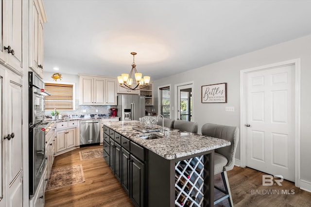 kitchen featuring an island with sink, a breakfast bar, dark wood-type flooring, sink, and appliances with stainless steel finishes