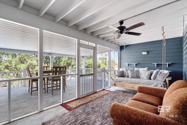 sunroom with ceiling fan and beam ceiling