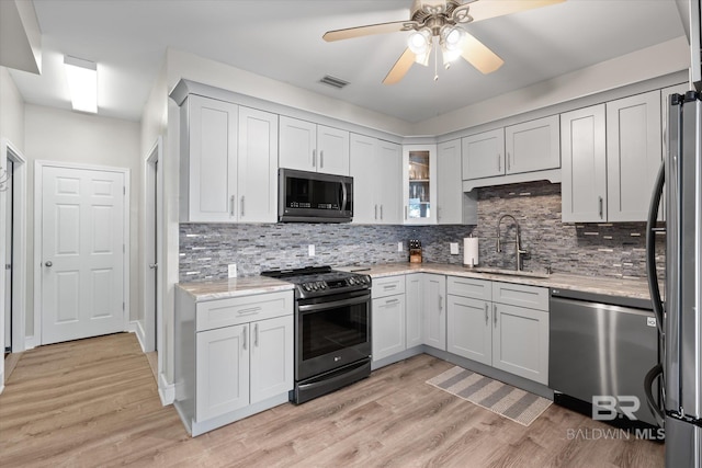 kitchen featuring light stone counters, appliances with stainless steel finishes, sink, and light hardwood / wood-style flooring