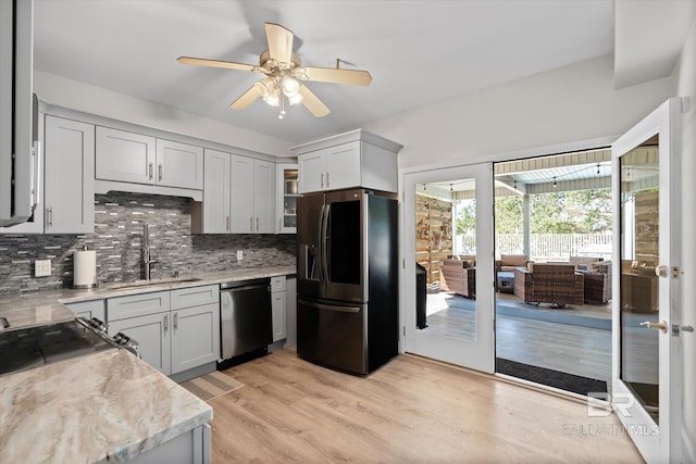 kitchen with sink, stainless steel appliances, light stone countertops, light hardwood / wood-style floors, and decorative backsplash