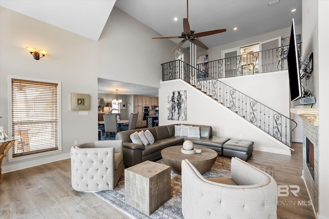 living room featuring ceiling fan with notable chandelier, hardwood / wood-style floors, and high vaulted ceiling