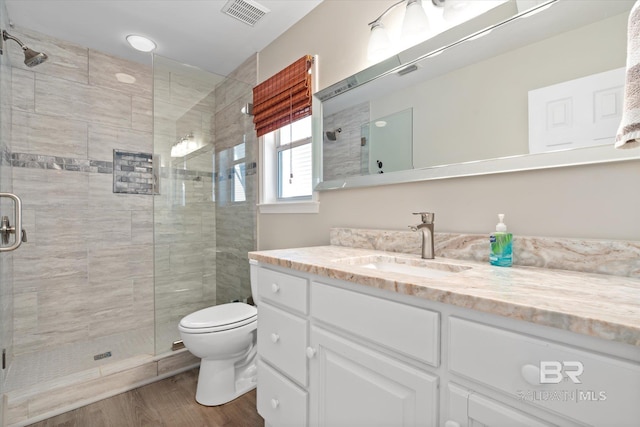 bathroom featuring hardwood / wood-style floors, vanity, a shower with door, and toilet