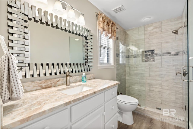 bathroom featuring hardwood / wood-style floors, a shower with shower door, vanity, and toilet