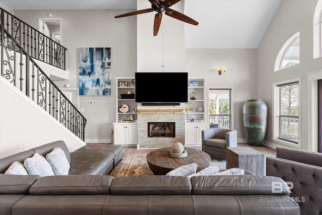 living room featuring ceiling fan, high vaulted ceiling, a wealth of natural light, and a stone fireplace