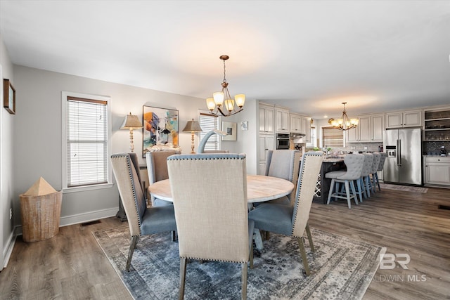 dining space with an inviting chandelier and dark hardwood / wood-style flooring