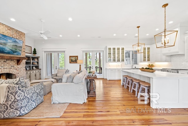 21151 Caveletti Cir, Fairhope, AL 36532 - living room with light wood-type flooring, a chandelier, recessed lighting, a ceiling fan, and a brick fireplace