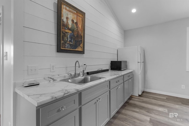 21151 Caveletti Cir, Fairhope, AL 36532 - kitchen with vaulted ceiling, gray cabinetry, wood finished floors, black microwave, and wooden walls