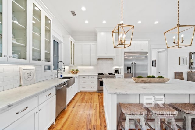 21151 Caveletti Cir, Fairhope, AL 36532 - kitchen with premium appliances, a chandelier, a breakfast bar area, white cabinetry, and recessed lighting