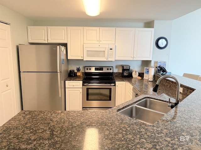 kitchen featuring dark stone counters, a sink, white cabinetry, and stainless steel appliances
