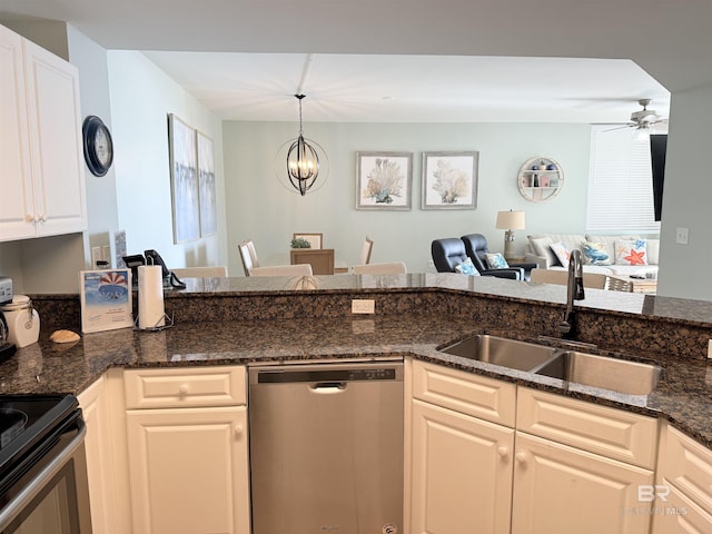 kitchen with a sink, open floor plan, dark stone counters, ceiling fan with notable chandelier, and stainless steel appliances