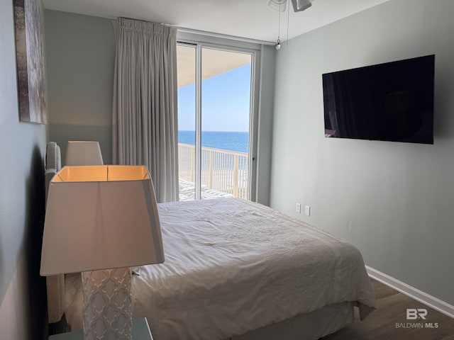 bedroom featuring access to exterior, baseboards, and wood finished floors