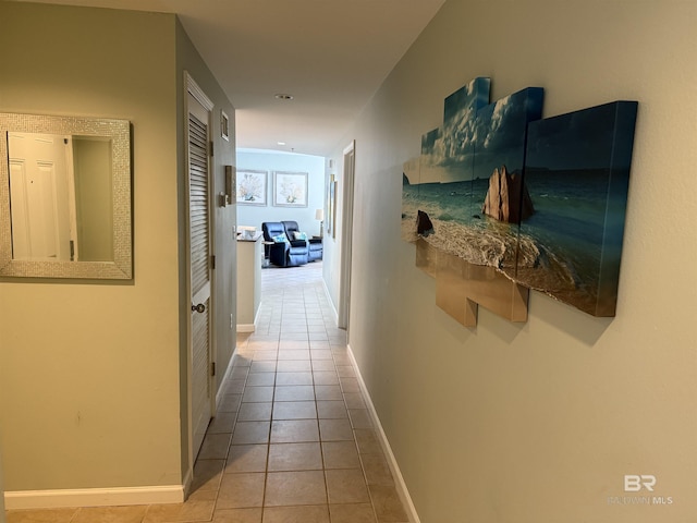 hallway featuring baseboards and tile patterned flooring