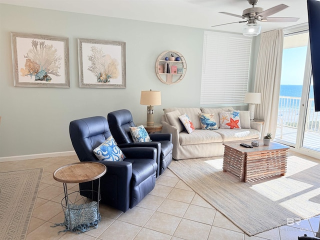 living area featuring a water view, light tile patterned floors, ceiling fan, and baseboards