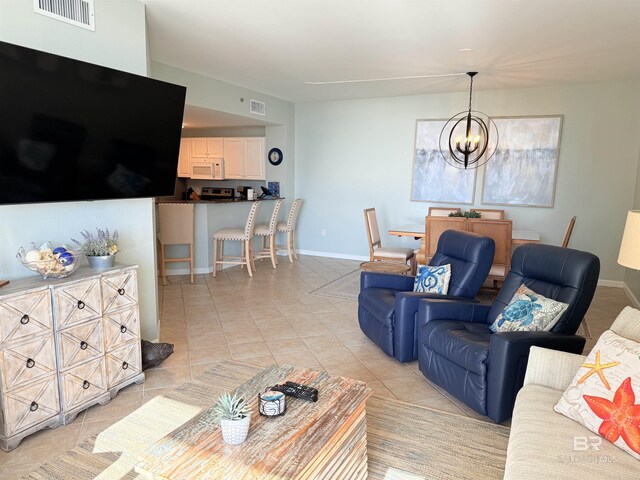 living area featuring visible vents, a notable chandelier, light tile patterned flooring, and baseboards