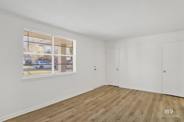 spare room with baseboards, light wood-style flooring, and crown molding