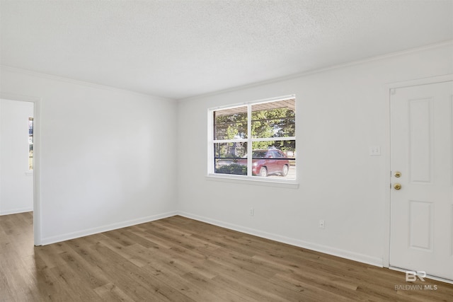 spare room with wood finished floors, baseboards, and a textured ceiling